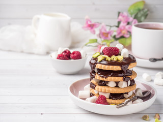 A sweet dessert of a chocolate cookie raspberry and marshmallow Cup of coffee on a light table.