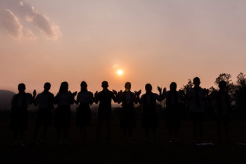 Silhouette of cheering young generation Stand on the mountain at sunset.,Business concept idea