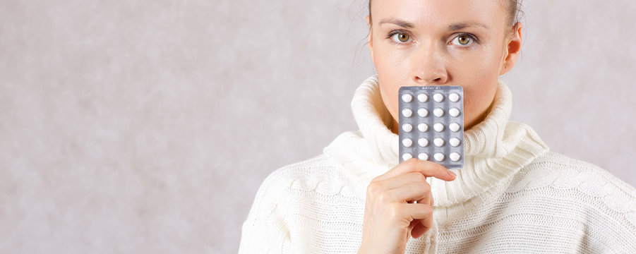 Young caucasian lady  dressed in a knitted sweater with medication. Closeup