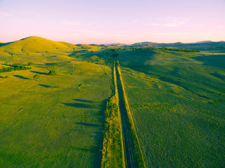 Straight rural road passing through countryside at sunset
