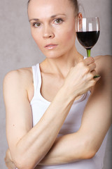 Young lady keeps a glass of red wine in her hand