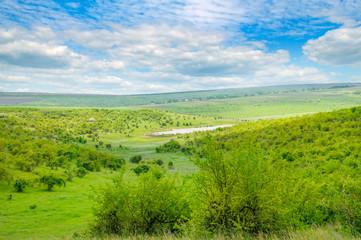 Fototapeta na wymiar Green field and blue sky. Picturesque hills formed by an old river terrace. Moldova. Agricultural landscape.