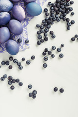 top view of violet easter eggs on napkin and blueberries on grey