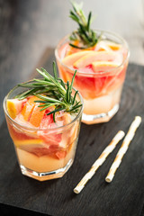 Two glasses of refreshing drink with grapefruit and rosemary served with straws. 
