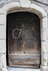 Time concept. Faded Christmas wreath on an antique house door. 