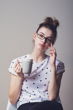 Beautiful young teenage girl in eyeglasses holding a coffee mug. Studio closeup portrait.