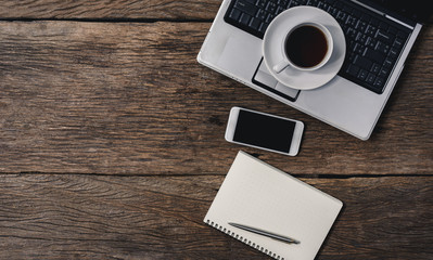 wooden table office stuff with notepad, laptop and coffee cup, notepad, pen, smartphone top view shot