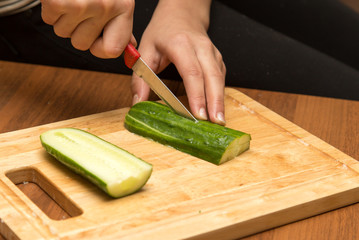 Slicing cucumber with a knife on the board