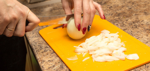 Slicing onions with a knife on the board