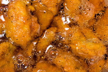 Frying the meat wrapped in breadcrumb on the pan, close up. Fried chicken in oil.