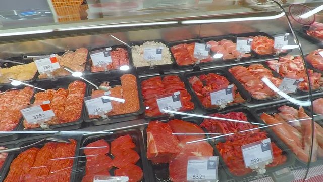 Selling a piece of meat in the store. Selection of different cuts of fresh meat raw red  in a supermarket.