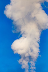 smoke from a pipe in the factory against a blue sky
