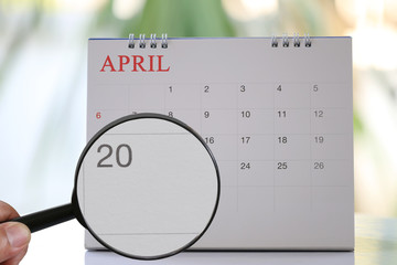 Magnifying glass in hand on calendar you can look Twentieth day of month,Focus number twenty in April.