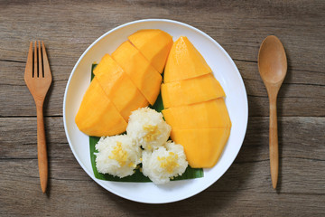 Mango and sticky rice in the white dish on wooden floor.
