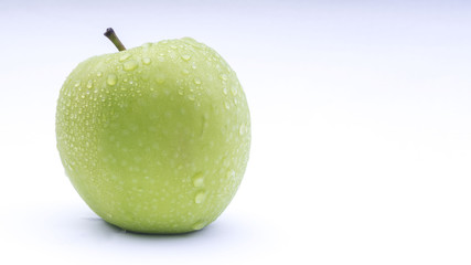 Closeup of green apple with water drops on white background. Selective focus.
