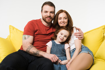 Portrait of smiling family sitting on couch isolated on white