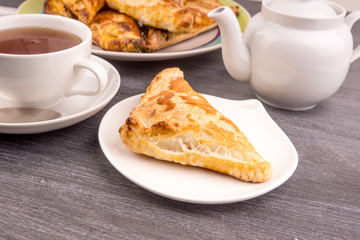 Delicious golden triangles of puff pastry on the table and a cup of tea - top view