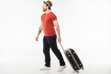 Stylish male tourist in hat carrying suitcase isolated on white, travel concept