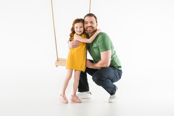 Daughter standing near swing and hugging father isolated on white