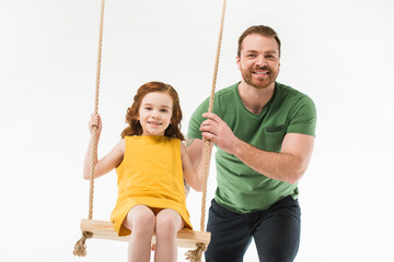 Smiling father riding little daughter on swing isolated on white