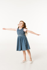 Little stylish kid in dress standing with wide arms isolated on white