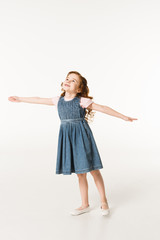 Naklejka premium Little stylish kid in dress standing with wide arms isolated on white