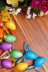 Fototapeta na wymiar Easter flower arrangement and colorful eggs on wooden surface