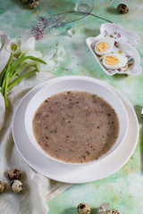 Polish traditional sour soup, zurek. Light background, eggs and tulips. White plate.