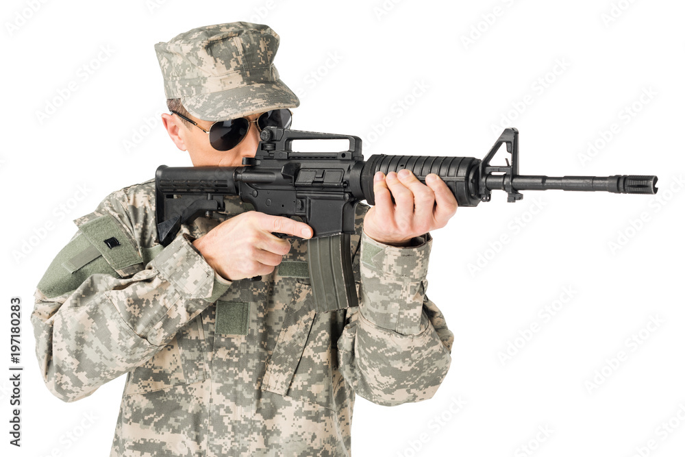 Wall mural Handsome army soldier wearing uniform aiming with gun isolated on white