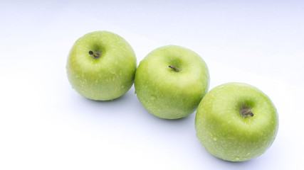 Closeup of green apple with water drops on white background. Selective focus.