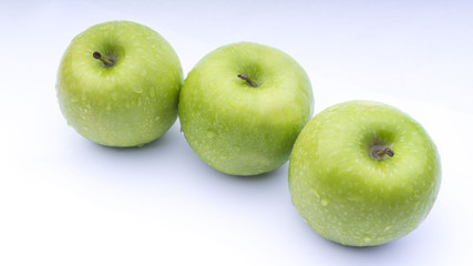 Closeup of green apple with water drops on white background. Selective focus.
