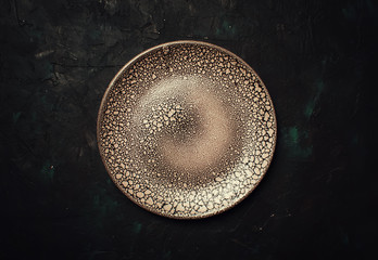 Empty brown plate on a dark background, top view