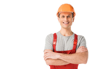 Smiling handyman in overalls with folded arms isolated on white