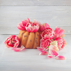 little cake, pie on wooden white kitchen plate with spring flowers tulips and roses, studio shot can be used as background