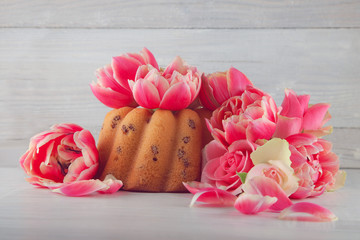 little cake, pie on wooden white kitchen plate with spring flowers tulips and roses, studio shot can be used as background