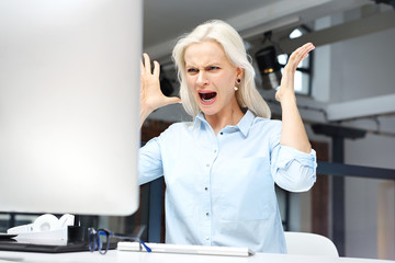 Nerwy i złość w pracy.
Wściekła młoda kobieta denerwuje się w pracy
