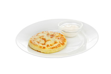 Cheese pancake on a plate with sour cream isolated white