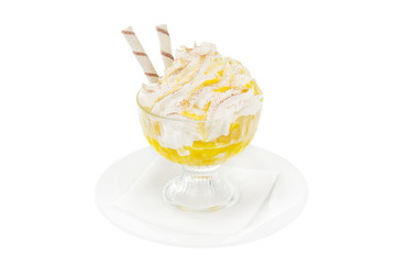 Ice cream dessert with whipped cream isolated on a white background in a high transparent glass with pineapple, apricot, orange, pumpkin jam, wafer tubules. Dessert for a menu side view