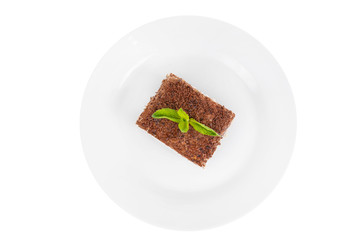 Rectangular piece of Tiramisu with a sprig of mint on a white plate. isolated on white background....