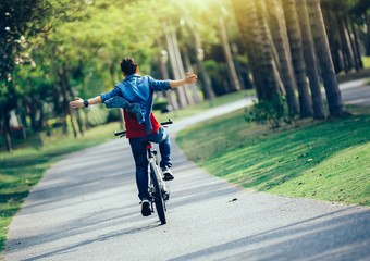 happy woman cyclist riding bike in spring tropical park