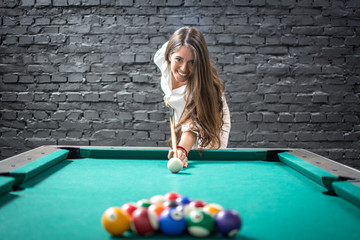 Happy business woman playing a game of billiards and preparing to break pyramid of balls on the...