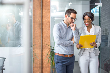 Concentrated man and woman examining business plan while standing in office