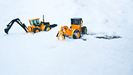 Two bulldozer standing side by side and a snowy winter.