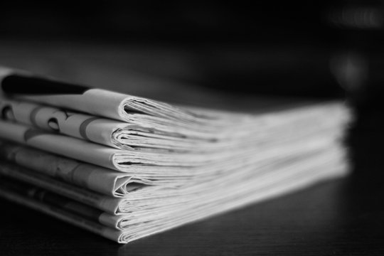 Pile of newspapers folded and stacked on dark background, concept for news and communication