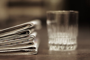 Pile of newspapers and glass on the table. Fresh daily papers with news in businessman office,...