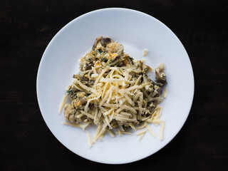 mushrooms fried with onions and cheese on a white plate, dark background, beautiful dish serving