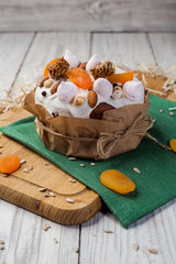 Easter cake (bread) decorated with candies, dried apricots and sunflower seeds on wooden background. Holidays concept