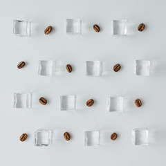 Coffee beans and ice cubes pattern on bright background. Flat lay summer drink minimal concept.