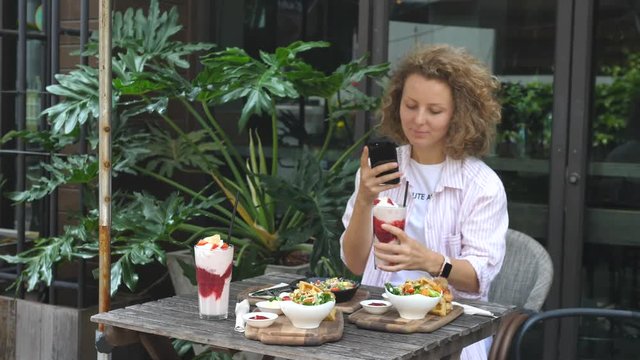 Stylish Young Woman Taking Photo Of Food With Phone Having Lunch In Restaurant