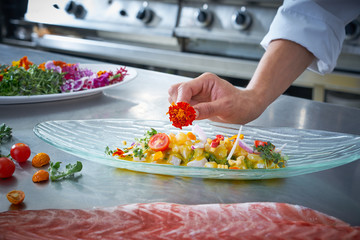Chef hands garnishing flower in ceviche dish